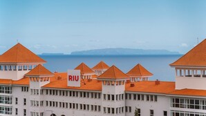 A coastal hotel with orange-tiled roofs and a sign reading "RIU".