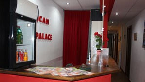 A reception area with a counter, a refrigerator, and a wall with 'PALACE' written on it.