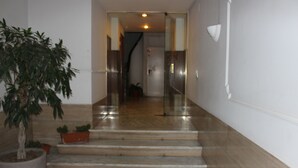 A hallway with marble flooring, a potted plant, and a staircase leading to another room.