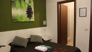 A hotel room with a bed, pillows, a painting, and a door leading to a bathroom.
