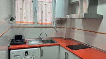 Een koelkast, kookgerei, borden en bestek