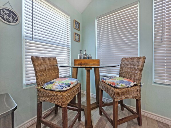 A corner room with two wicker chairs, a small wooden table, and white blinds. - A Sandy Hope- Pet-Friendly Family Beach Retreat Sleeps12 3-Min Walk to the Beach (Crystal beach)