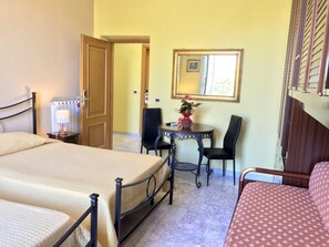 A hotel room with two beds, a desk with a chair, a mirror, and a window with blinds. - Bed Breakfast Il Tesoro (Rome)