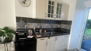 A kitchen with a built-in oven, microwave, and sink, with patterned backsplash tiles and white cabinets. - Chez Sandrine (La Gacilly)