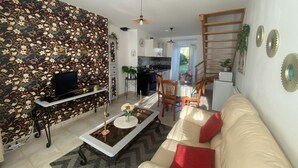 A modern living room with a sofa, a coffee table, a TV, and a patterned wall. - Chez Sandrine (La Gacilly)