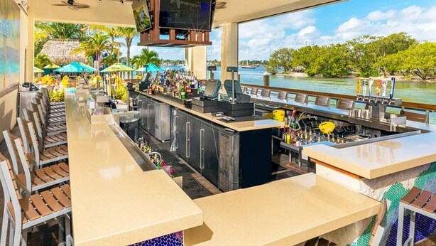 A bar area with a view of a body of water, wooden ceiling, and bar stools. - Charming Beachside Studio | Steps to the Beach (Hollywood)