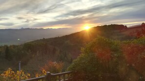 Ein Sonnenuntergang über einer Berglandschaft, im Vordergrund ein Holzzaun.
