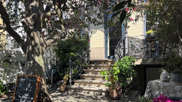 Un patio con una pizarra, mesas al aire libre, una escalera y plantas en macetas.