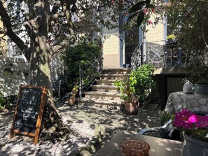 A courtyard with a chalkboard sign, outdoor seating, a staircase, and potted plants. - Vila Camélia - Amor Suite with private terrace (Porto)