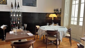 Un comedor con una mesa redonda, sillas, un mueble para vinos y una lámpara.