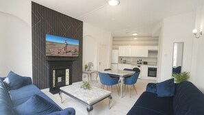 A modern living room with a fireplace, a dining area, and a kitchen. - Stylish 2-Bedroom Apartment in the Heart of Soho (London)