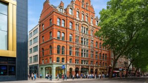 A historic red brick building with multiple stories, large windows, and a prominent corner entrance. - Stylish 2-Bedroom Apartment in the Heart of Soho (London)