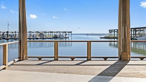 A wooden deck with a metal railing overlooking a marina with boats and docks.