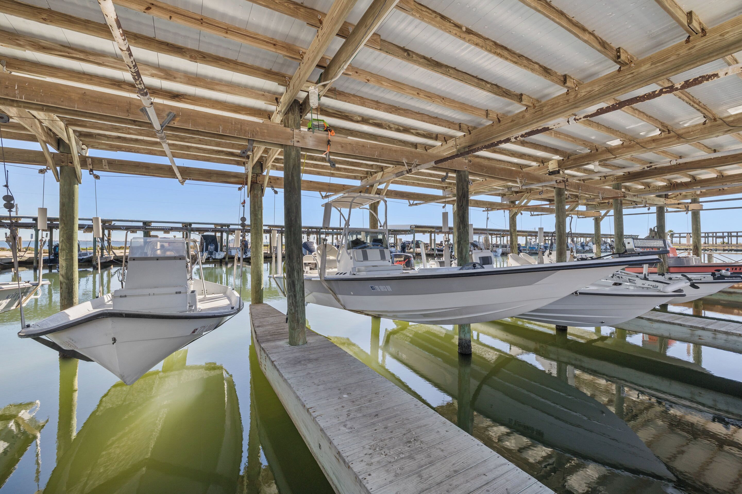 Un muelle cubierto con varias embarcaciones amarradas bajo una estructura de techo de madera.