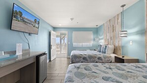 Habitación de hotel con cama, escritorio, televisor en la pared y vista al exterior.