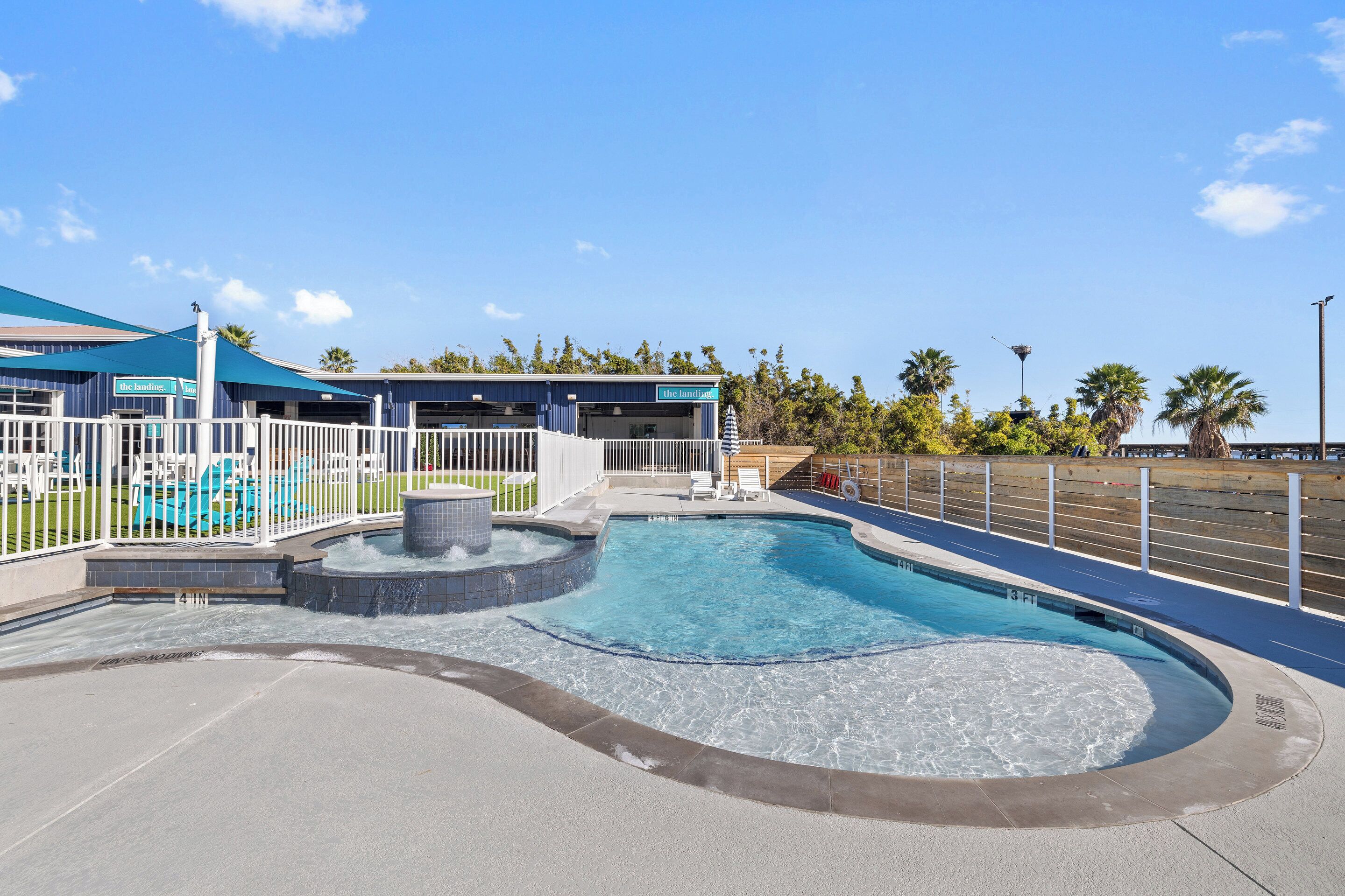 A swimming pool with a water feature, a covered seating area, and a building with a sign that reads "The Lagoon."
