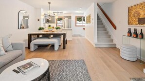 A modern living room with a sofa, coffee table, and a dining area with a table and chairs. - Updated Ski In 3-bedroom townhome in Whistler (Whistler)