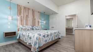 Une chambre à coucher comprenant un lit, une étagère intégrée, un luminaire fixé au mur et une porte donnant accès à une salle de bain.