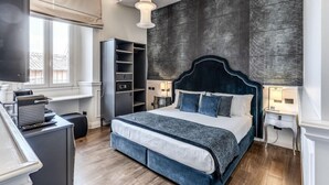 A modern bedroom with a large bed, built-in shelving, and a desk. - Rhea Silvia Luxury Rooms Spagna (Rome)