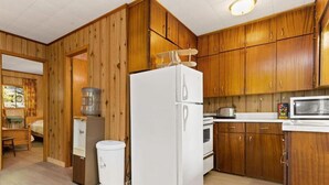 Une cuisine de taille réduite, dotée de meubles de rangement en bois, d’un réfrigérateur, d’un four à micro-ondes et d’un grille-pain.