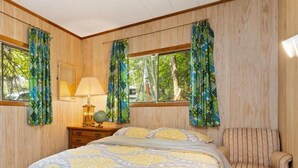 Une chambre à coucher avec un lit, une chaise, une table de chevet avec une lampe et des rideaux.