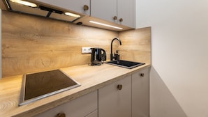Une cuisine moderne avec un plan de travail en bois, une bouilloire noire, un évier et une hotte aspirante intégrée.