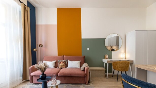 Un salon moderne comprenant un canapé, une petite table ronde, un fauteuil et un bureau avec une chaise.