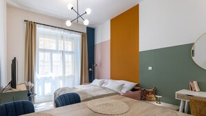Une chambre d’hôtel avec deux lits, un bureau, une chaise, une table ronde et une fenêtre avec des rideaux.
