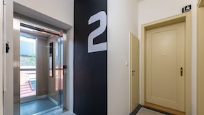 Un couloir avec une porte en verre donnant sur un espace piscine, un mur noir avec un panneau blanc portant le chiffre « 2 », et une porte beige avec un panneau indiquant le chiffre « 4 ».
