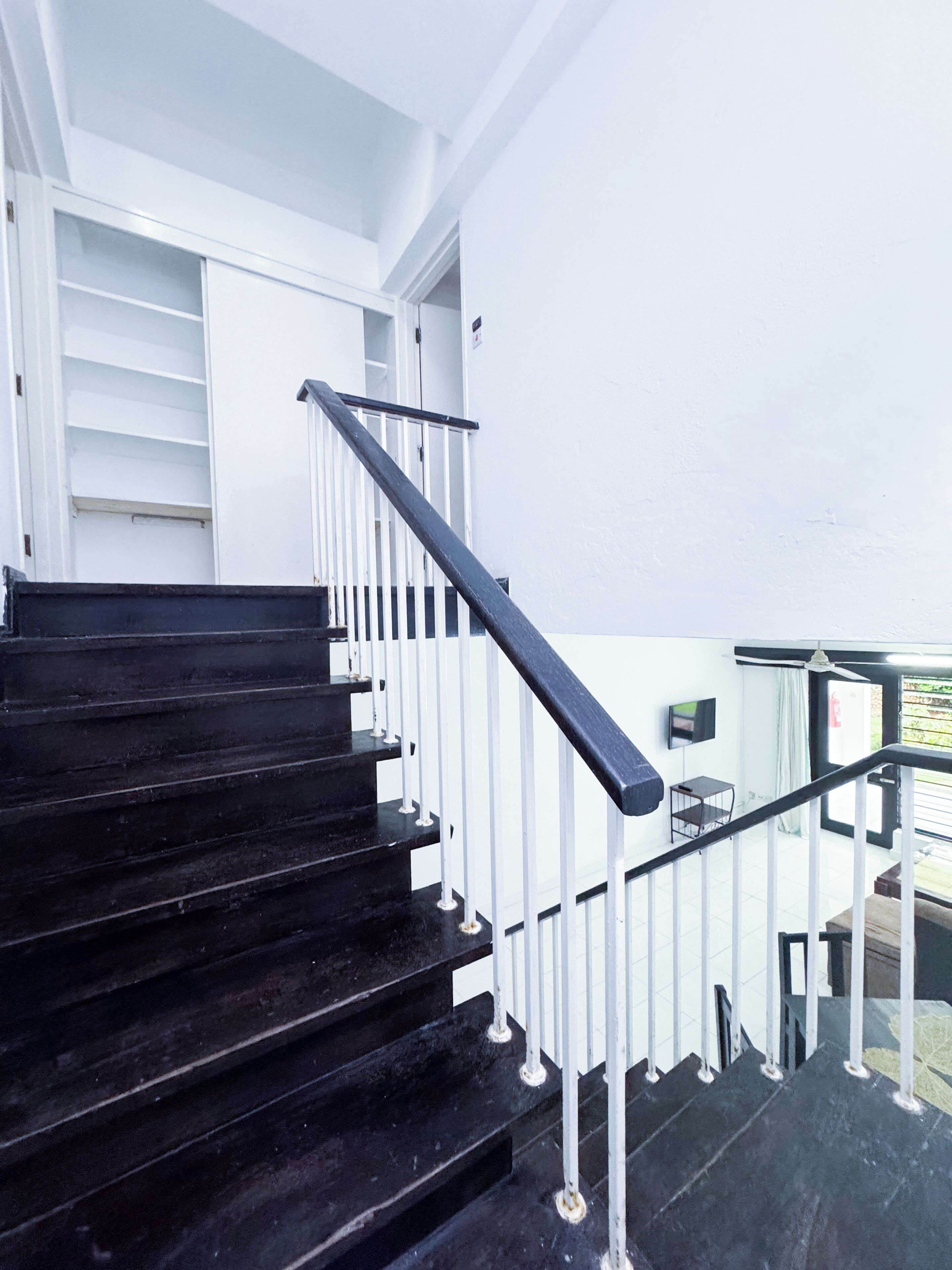 A staircase with black steps and white railings, leading to an upper floor.