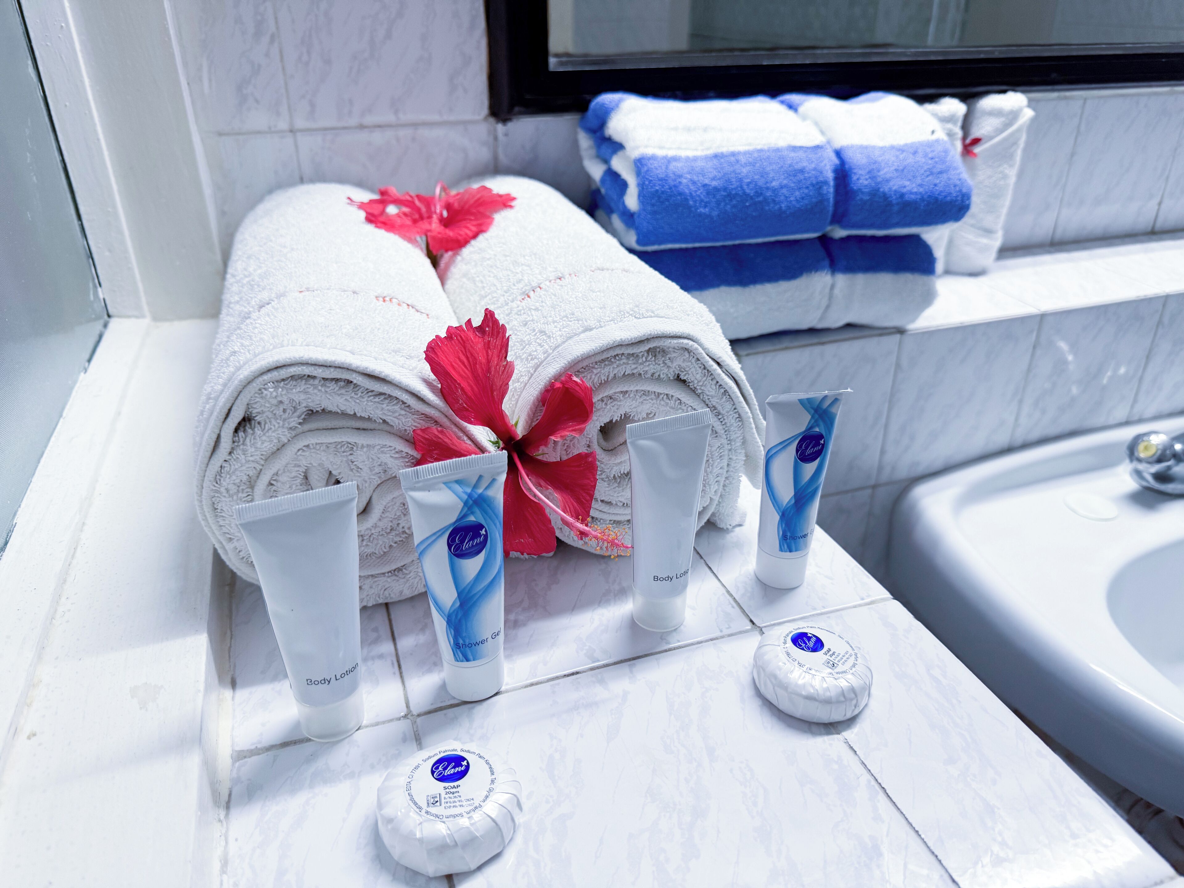 Un baño con toallas ordenadamente dobladas, loción corporal, gel de ducha y una pastilla de jabón.