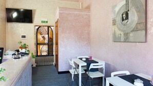 A hotel room with a desk, chairs, a TV, a painting, and a door leading to a staircase. - Magic Guest House (Rome)