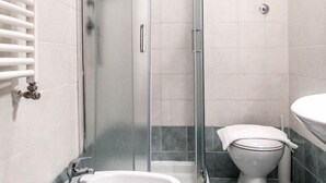 A bathroom with a glass-enclosed shower, a toilet, and a sink. - Magic Guest House (Rome)