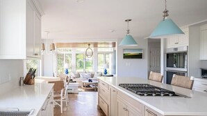 A modern kitchen with a large island, white cabinetry, and pendant lighting.