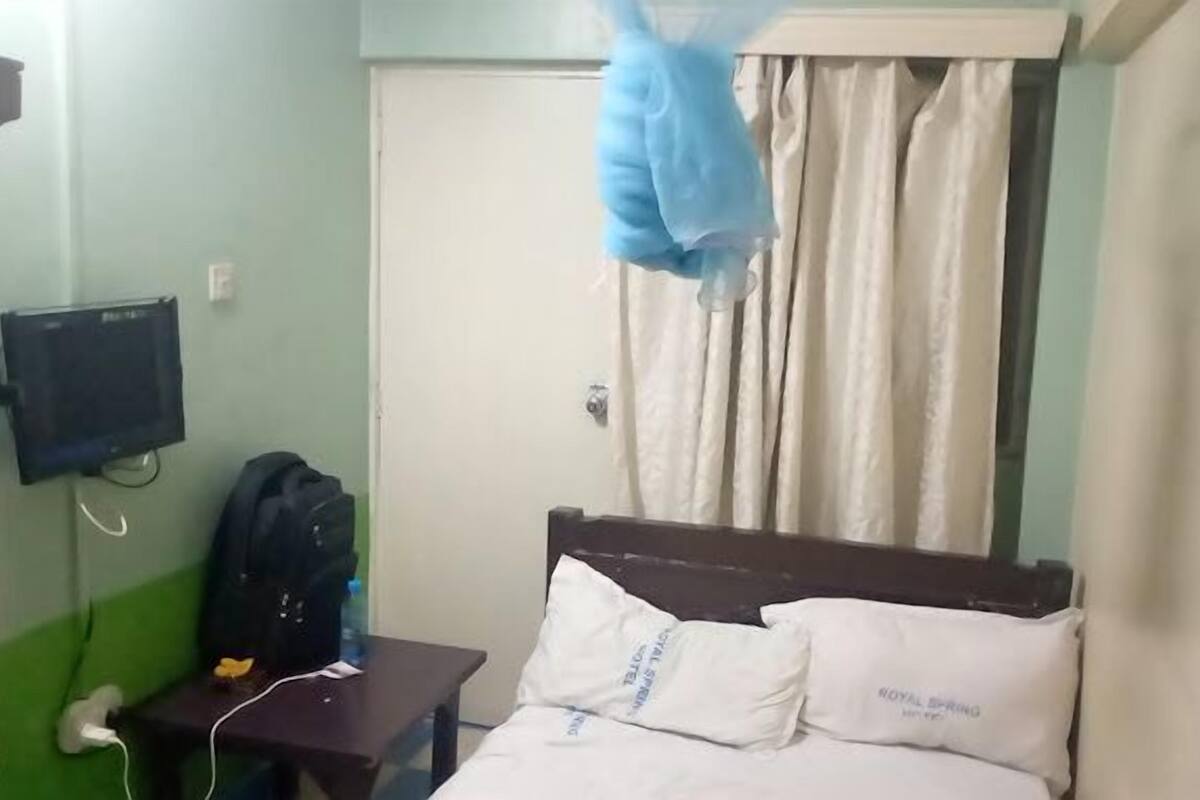 A hotel room with a bed, a nightstand, a television, and a curtain.
