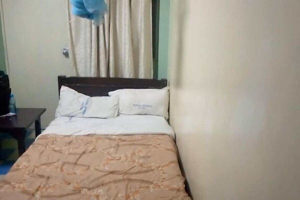 A bed with a patterned bedspread, a wooden headboard, and two pillows.