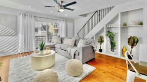 A modern living room with a grey sofa, a round coffee table, and a staircase with a 'LOVE' sign.