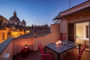 Une terrasse sur le toit, avec une table dressée pour deux personnes, une lanterne et une vue sur un bâtiment historique doté de coupoles.