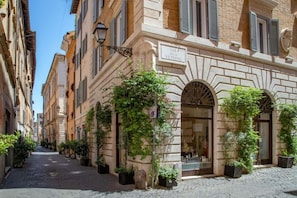 A narrow cobblestone street lined with historic buildings, one with a sign reading "Via della Vetrina."