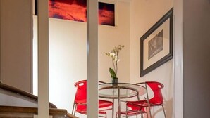 Una escalera con barandillas de vidrio que conduce a un comedor con sillas rojas y una mesa.