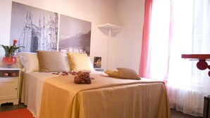 Un dormitorio con una cama, una mesita de noche, una planta en maceta y un cartel en la pared.
