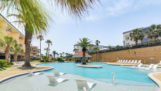 A swimming pool with multiple lanes, surrounded by lounge chairs and palm trees. - 3 Pools and 2 Hot Tubs, Walk to the Beach (Galveston)