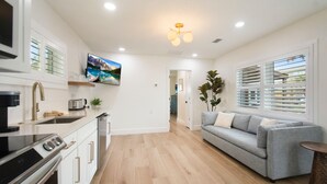 A modern kitchen with white cabinets, a built-in oven, and a countertop with a coffee maker. - Coastal Blue Escape (St. Augustine)