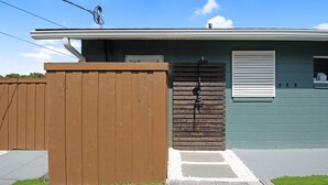 A residential building with a front porch, a wooden fence, and a garage door. - Coastal Blue Escape (St. Augustine)