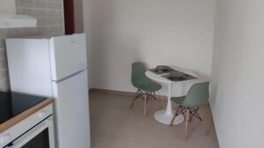 A compact kitchen with a white refrigerator, a stove, and a hanging light fixture. - E&S Apartment (Syracuse)
