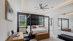 Une chambre à coucher moderne avec un lit à baldaquin, un bureau avec un ordinateur portable, une chaise et un grand miroir.