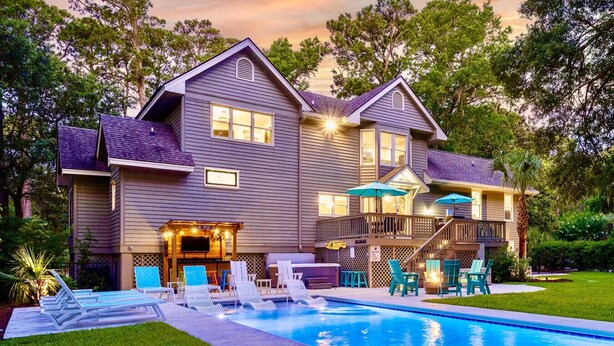 Une maison à deux étages dotée d’une piscine, d’un espace salon extérieur et d’un patio couvert.