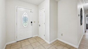A hallway with two white doors, one with a stained glass design, and a tiled floor. - 4 bedroom home in Bridge City (Bridge City)