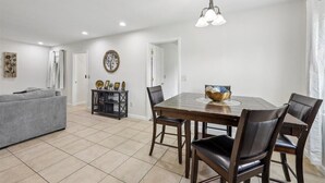 A dining area with a wooden table and chairs, a chandelier, and a sofa in a modern interior. - 4 bedroom home in Bridge City (Bridge City)