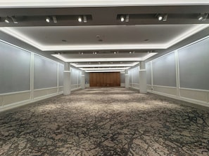 A hotel corridor with a carpeted floor, recessed lighting, and a wooden door at the end. - Virginia Guesthouse Hotel (Charlottesville)